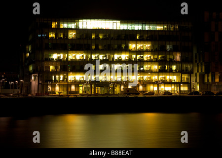 Office building with lights on Sir John Rogerson s Quay Dublin with River Liffey in the foreground Stock Photo