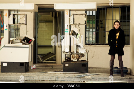 Young woman waiting in ruined gas station Stock Photo