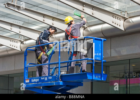 Window cleaners on an elevated scissor platform Stock Photo