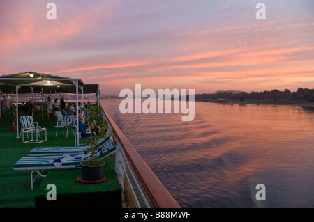 View of tourists relaxing on the upper deck of a cruise boat on the River Nile at Sunset Egypt Middle East Stock Photo