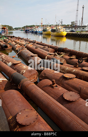 Old rusting steel pipes and boilers floating in harbour Leba Poland Stock Photo