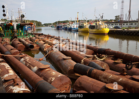 Old rusting steel pipes and boilers floating in harbour Leba Poland Stock Photo