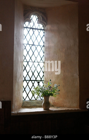 Flowers In Vase on Cill of Leaded Window at St Oswald's Church Windrush Valley Cotswold Hills Stock Photo