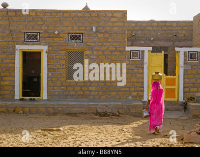 Indian woman carries water pot on head Khuri desert Rajasthan India Stock Photo