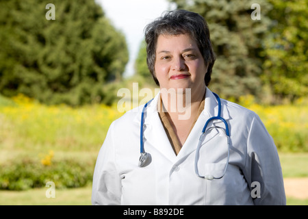 Middle aged female doctor stands outside in a field. Stock Photo