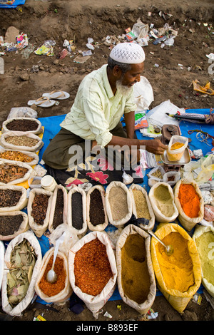 Spices for sale at a street market spice stall, with street seller. Hazira, Surat, Gujarat. India. Stock Photo