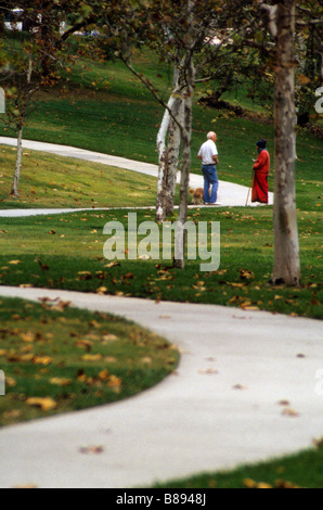 Man walks down curved sidewalk through park individual solo alone sole lone single one lonely solitary separate only person Stock Photo