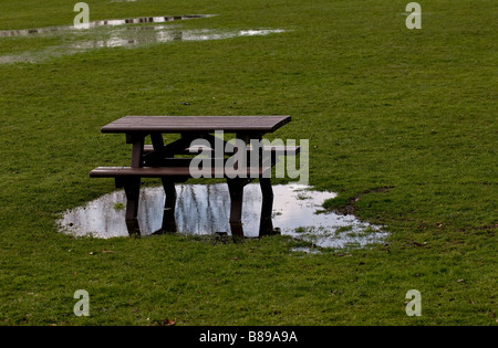 A wooden picnic table in a flooded field. Stock Photo