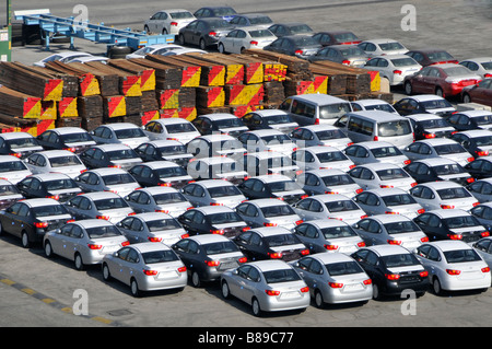 Bahrain looking down close up on dockside storage of imported new cars and large piles of timber awaiting distribution Stock Photo