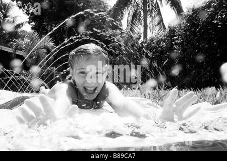 child playing on water slide on grass Stock Photo