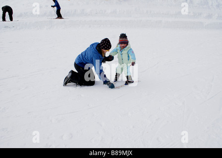 Ski instructor showing  2 year-old girl the snowplow position on beginner's slope at Snoqualmie Summit, Washington USA Stock Photo