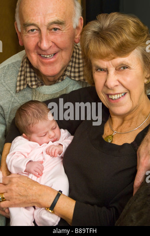 Vertical portrait of proud grandparents cuddling their newborn granddaughter Stock Photo