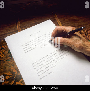 An old womans hand puts her signature on her testament Stock Photo