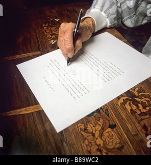 An old womans hand puts her signature on her testament Stock Photo