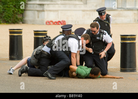 Horizontal close up of a man on the floor resisting arrest and being handcuffed by numerous police in central London. Stock Photo