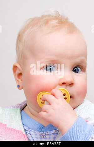 Suckling baby 7 months old with yellow dummy Stock Photo
