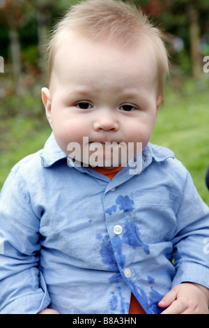 Baby boy sitting in park with drink spilt down shirt (with signed model release - available for commercial use) Stock Photo