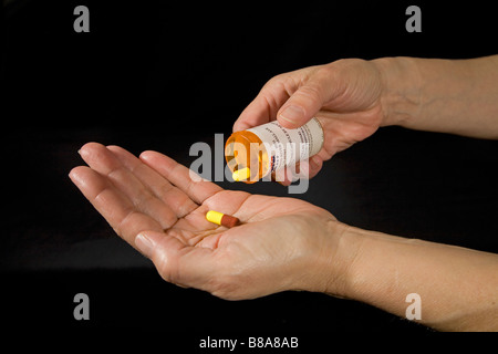 Prescription drugs in the form of capsules being removed from their bottle Stock Photo