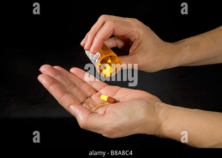 Prescription drugs in the form of capsules being removed from their bottle Stock Photo