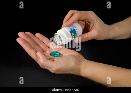 Over the counter drugs such as Aleve in the form of capsules being removed from their bottle Stock Photo