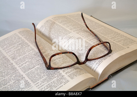 A pair of common reading eye glasses or spectacles lying on a dictionary Stock Photo