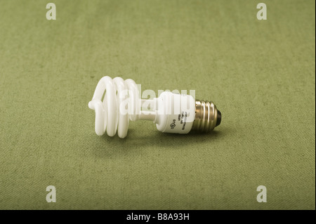 Eco-friendly concept energy saving cost saving cost efficient compact fluorescent light bulb isolated on green Stock Photo