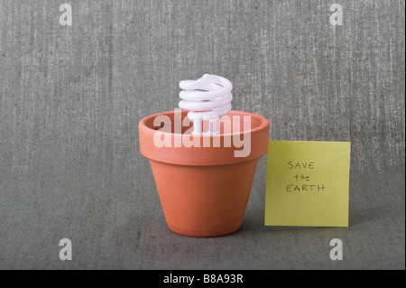 Save the Earth eco friendly energy saving compact fluorescent bulb in clay pot Earth Day climate crisis environmental responsibility concepts. Stock Photo