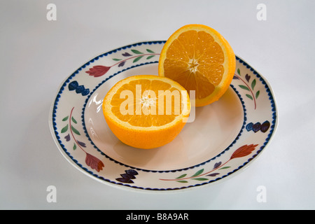 STILL LIFE FRUIT VEGETABLE Two halves of a navel orange sliced evenly on a plate Stock Photo