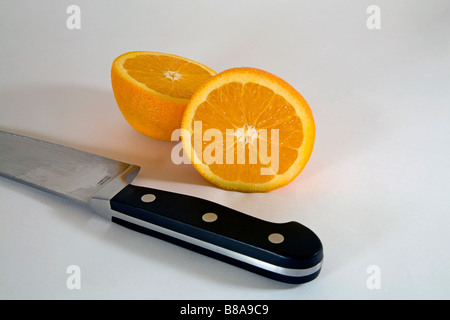 STILL LIFE FRUIT VEGETABLE Two halves of a navel orange sliced evenly in two by a large kitchen or butcher knife Stock Photo