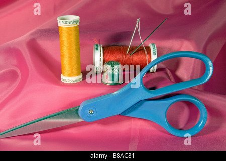 A sewing kit containing needles thread on spools scissors and thimble Stock Photo