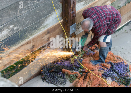 man using angle grinder on beach Stock Photo