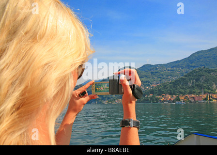 Young woman taking photograph from a passenger ferry crossing from Bellagio to Varenna on Lake Como Stock Photo