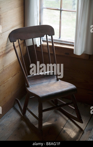 Photograph of a wooden rocking chair in front of a window. Stock Photo