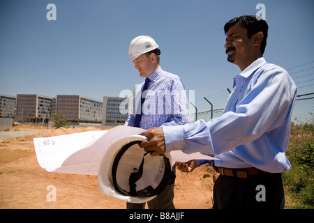 Two men discuss plans at a construction site in Bangalore, India. Stock Photo