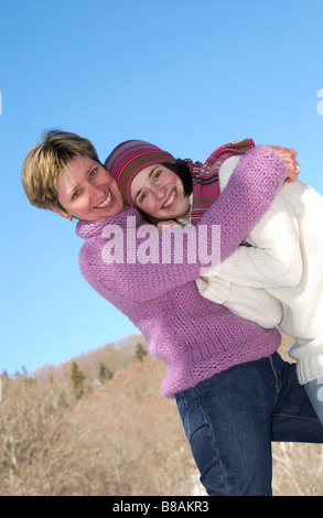 Portrait of smiling mother and daughter hugging outside in winter Stock Photo