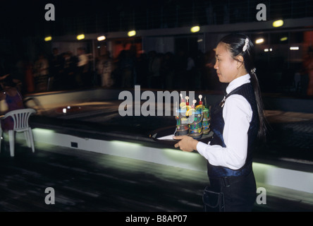 philipino waitress serving drinks on outside deck of a cruise ship Stock Photo