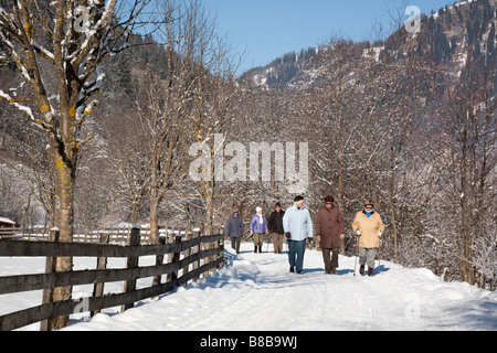 People walking on Winterwanderweg cleared trail along Alpine valley with snow in winter. Rauris Rauriser Sonnen Valley Austria Stock Photo