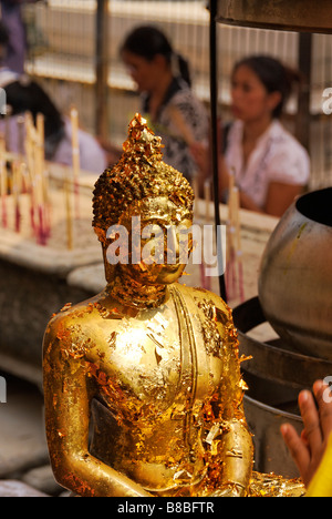 Face of Buddha statue with pieces of gold leaf offerings - Wat Phra Kaew and the Grand Palace in central Bangkok Thailand Stock Photo