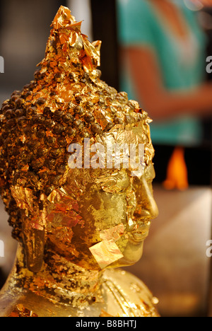 Face of Buddha statue with pieces of gold leaf offerings - Wat Phra Kaew and the Grand Palace in central Bangkok Thailand Stock Photo