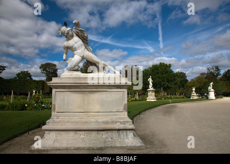 Dramatic blue sky behind Sculptures in Tuileries sculpture garden outside world famous Louvre art  museum Paris France pigeon sits on head of statue Stock Photo