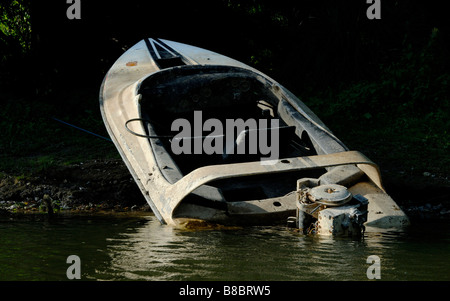 Burnt out speedboat and outboard motor on bank of the River Thames, Staines, Middlesex, England Stock Photo
