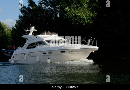 Sealine F43 flybridge motor cruiser with couple at the helm on the River Thames near Runnymede, Egham, Surrey, England Stock Photo