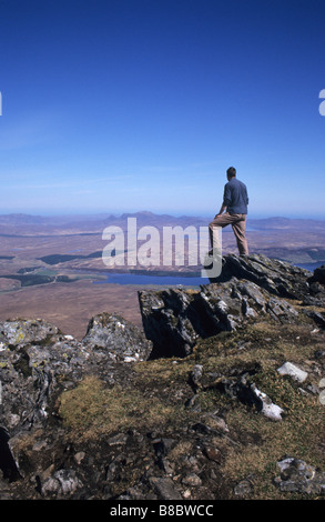 Hillwalker standing near summit of Ben Klibreck munro looking North towards Altnaharra Loch Naver Sutherland Scotland Stock Photo