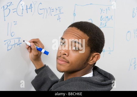 Male student writing maths equations on whiteboard Stock Photo