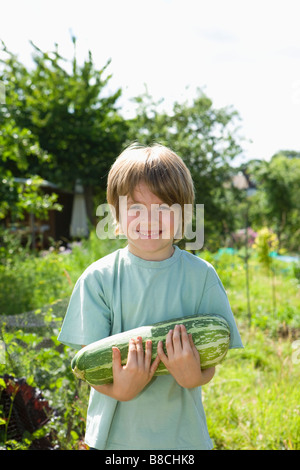 Boy holding marrow in garden, portrait Stock Photo