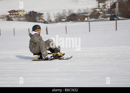 Rauris Austria EU January Young girl sitting on a ski sledge with steering wheel descending the toboggan run of Kreusboden Stock Photo