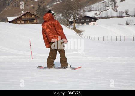 Rauris Austria EU January Young man in a large shiny brown ski parka descending the piste on a snowboard Stock Photo
