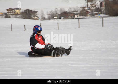 Rauris Austria EU January Young boy sitting on a plastic sledge descending the toboggan run of Kreusboden Stock Photo