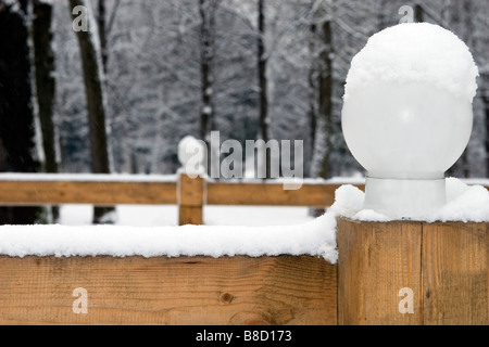 Winter forest road surrounded with wood fence and white sphere lamps. Stock Photo