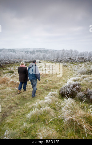 Two walkers walking towards Padley Gorge following a winter hoarfrost in The Peak District Stock Photo